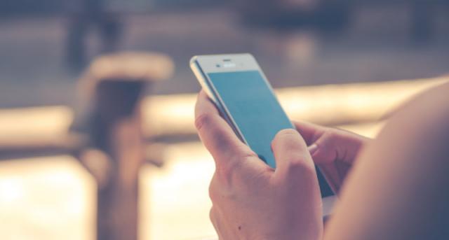 Close-up of a woman's hands holding an iPhone with a blue screen